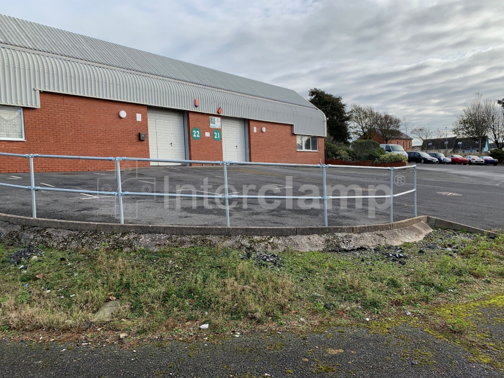 Interclamp key clamp fittings and tube used to create a durable guardrail at an industrial car park, ensuring a safe and protected parking area.